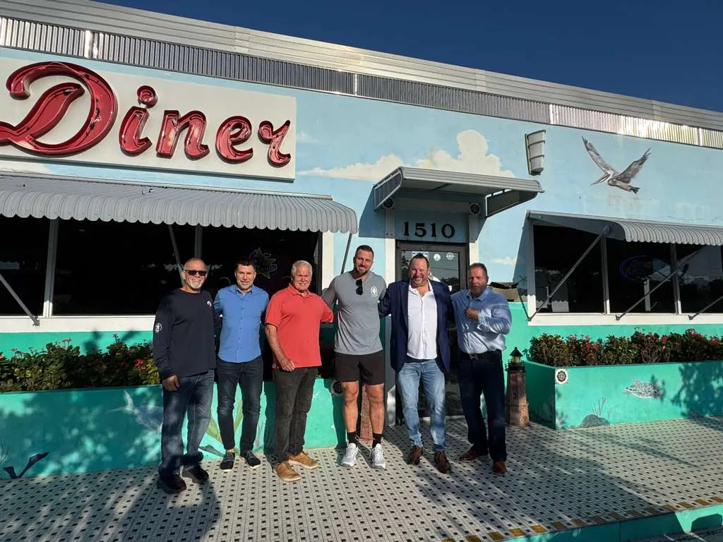 Michael Fineman with five men from an Authority Reset cohort, arm in arm outside a diner in the sun